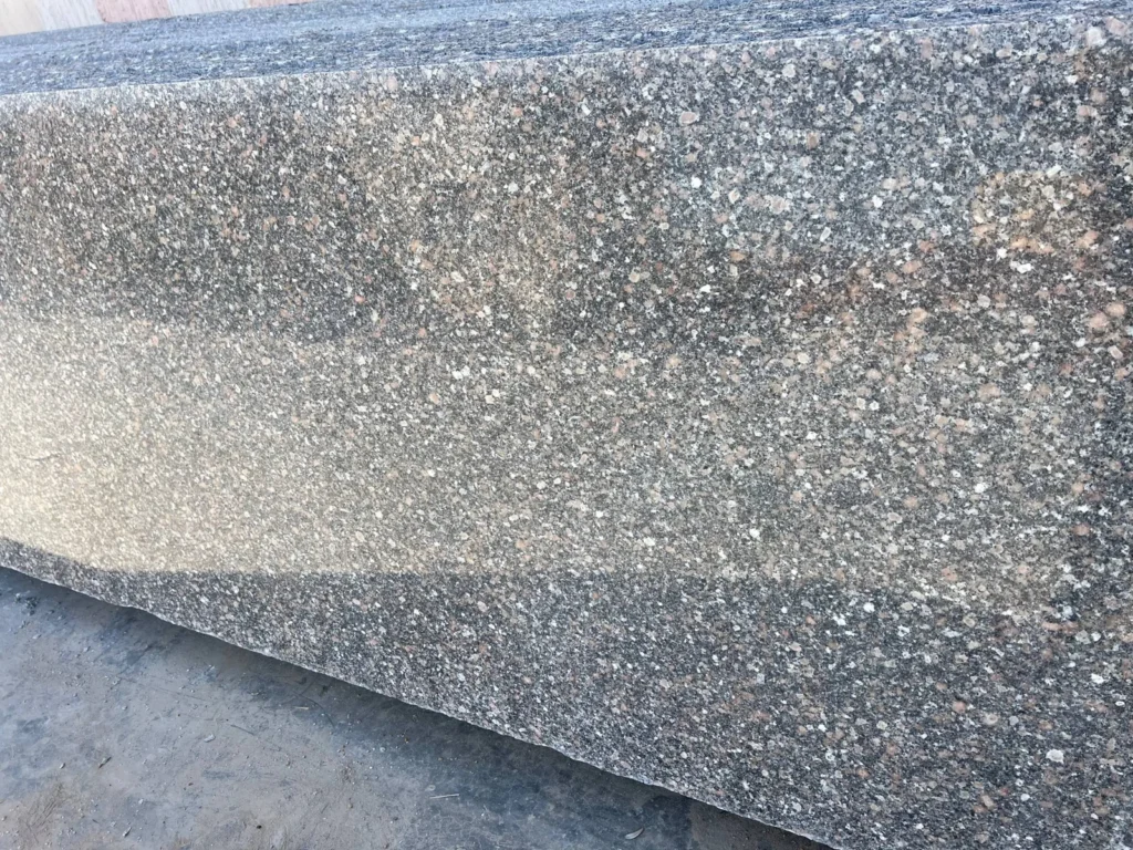 Grey-and-black speckled stone slab with scattered pink and pale grains.