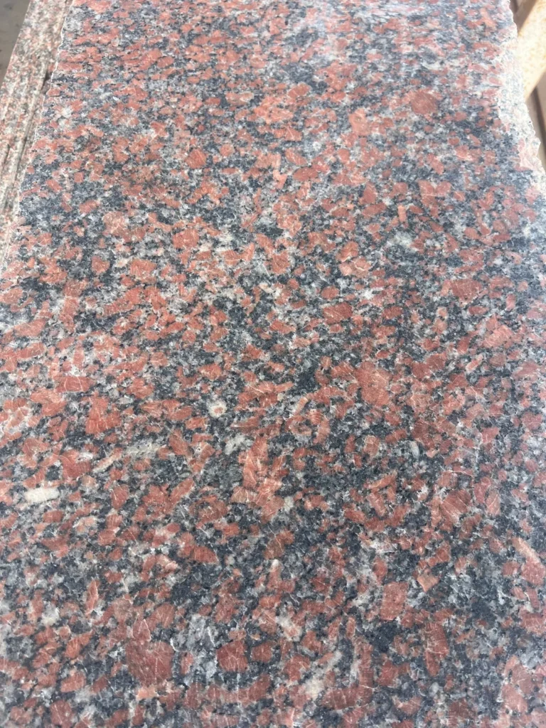 Close view of a red-pink, black and grey coarse-grained stone surface.