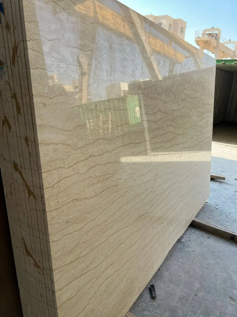 Reflective beige stone slab with fine wavy brown veins standing in an outdoor yard.