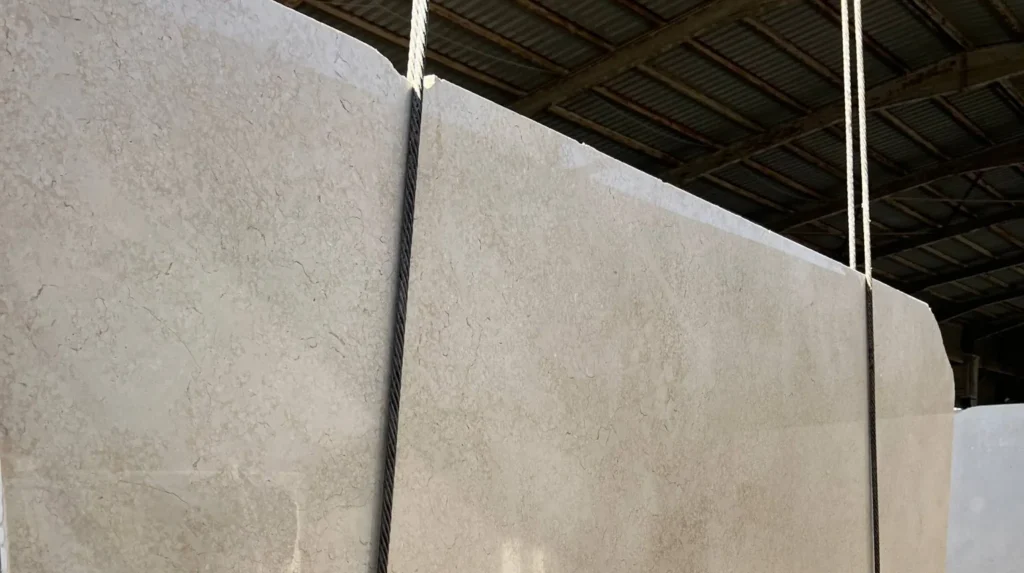 Large light-beige polished stone slab with fine veining, reflecting the hall around it.