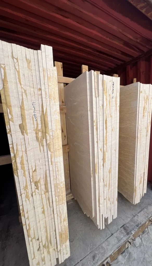 Upright pale stone slabs with timber supports inside an open red shipping container.