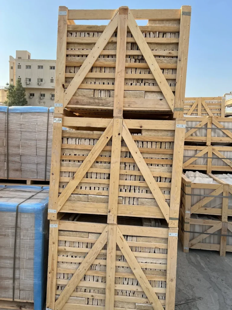 Three stacked timber crates with pale stone pieces visible between the slats in an outdoor yard.