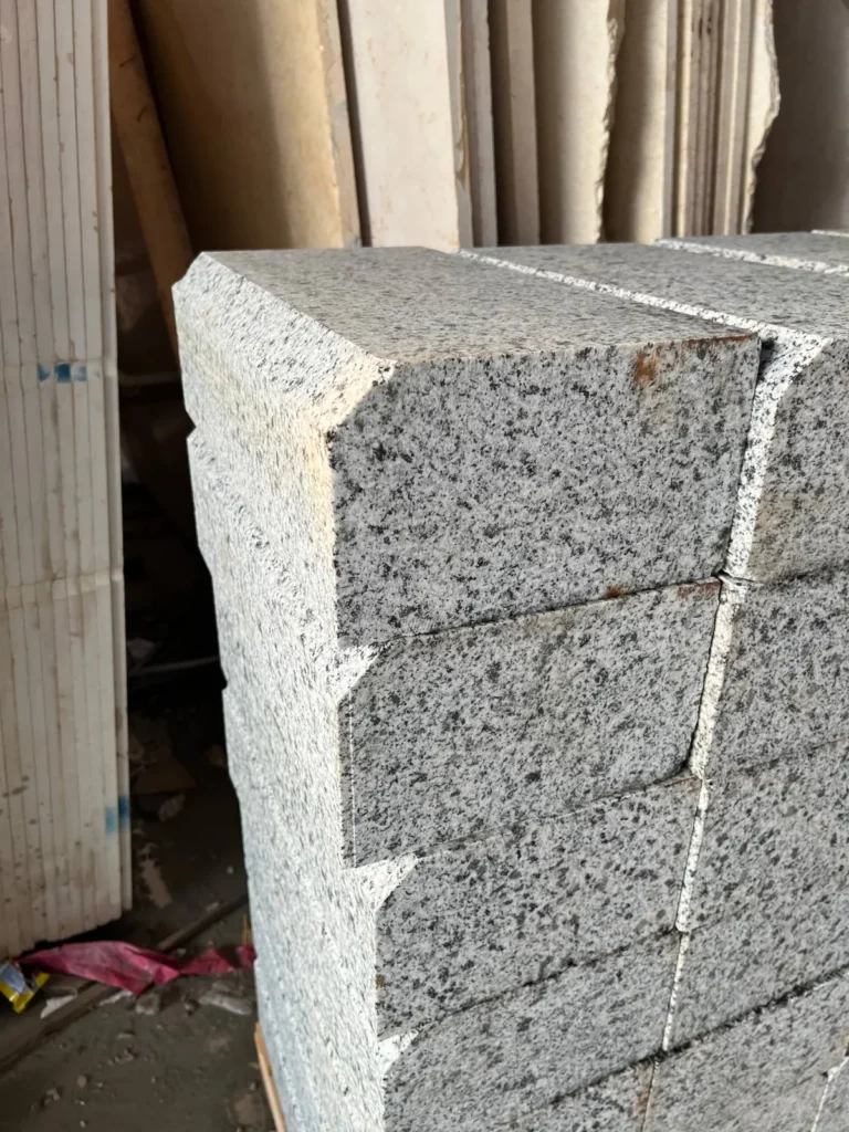 Close view of thick grey-and-black speckled stone pieces stacked in rows, showing faces and edges.